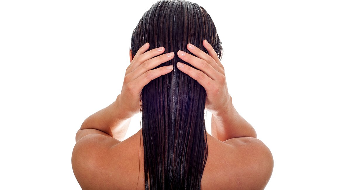 Eine jungen Frau fährt sich mit beiden Händen durch ihre langen schwarzen Haare